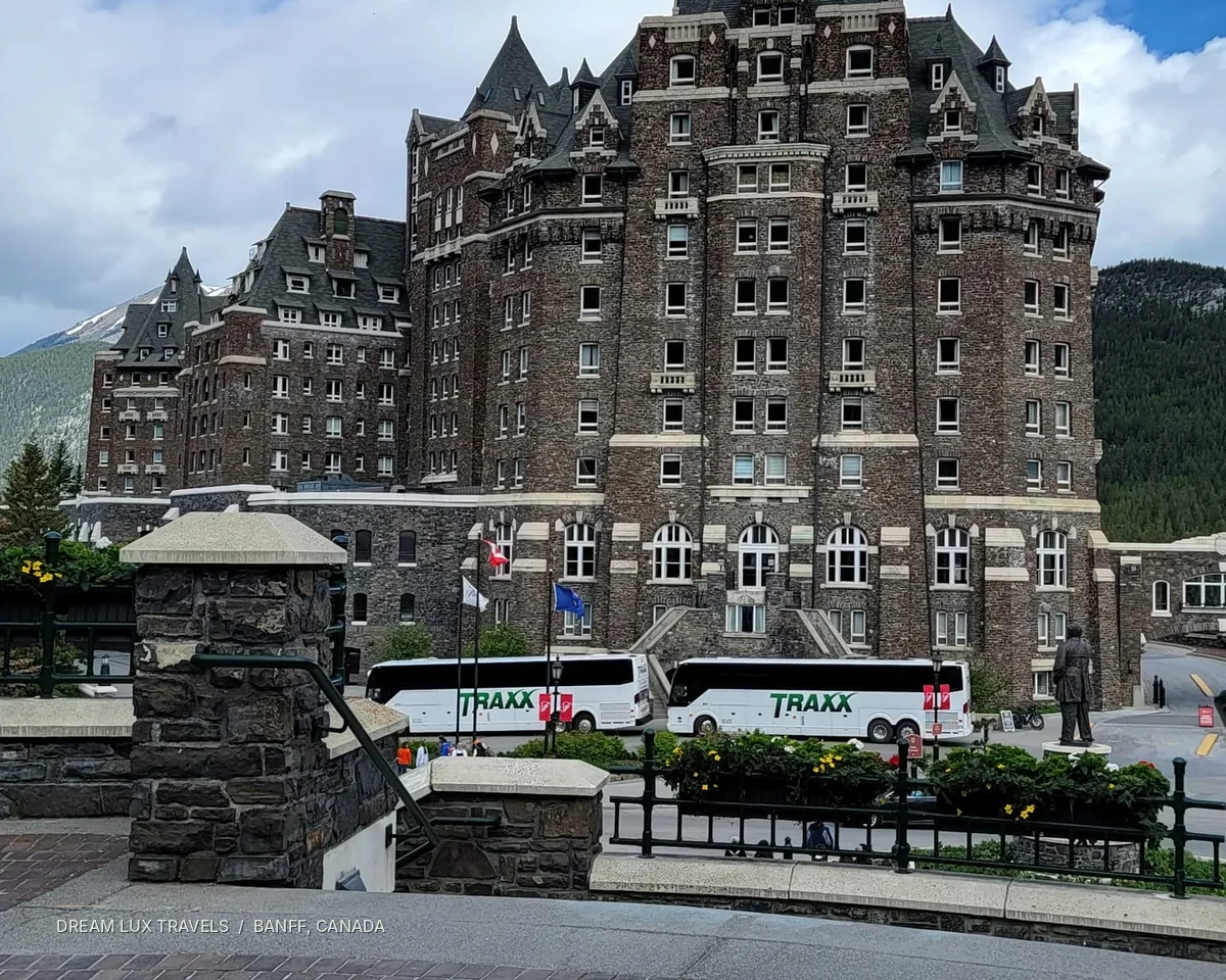 Fairmont Banff Springs stone hotel towers against a bright blue sky.