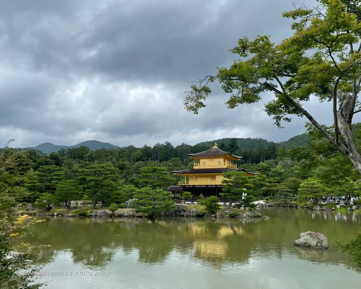 Golden Pavilion temple reflected in a pond amid landscaped trees in Kyoto.