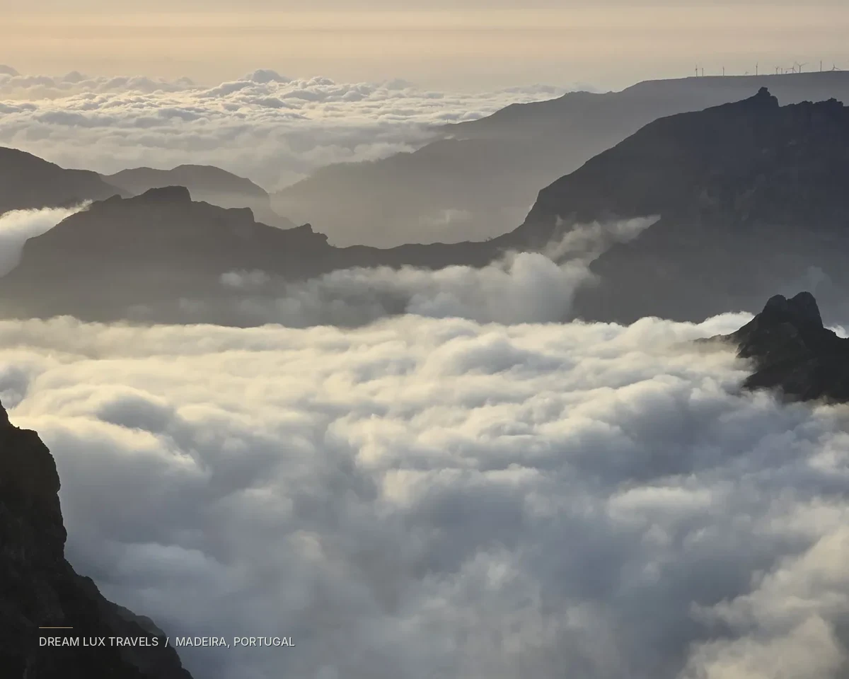 Mountain ridges rising through a sea of clouds on Madeira at golden hour.